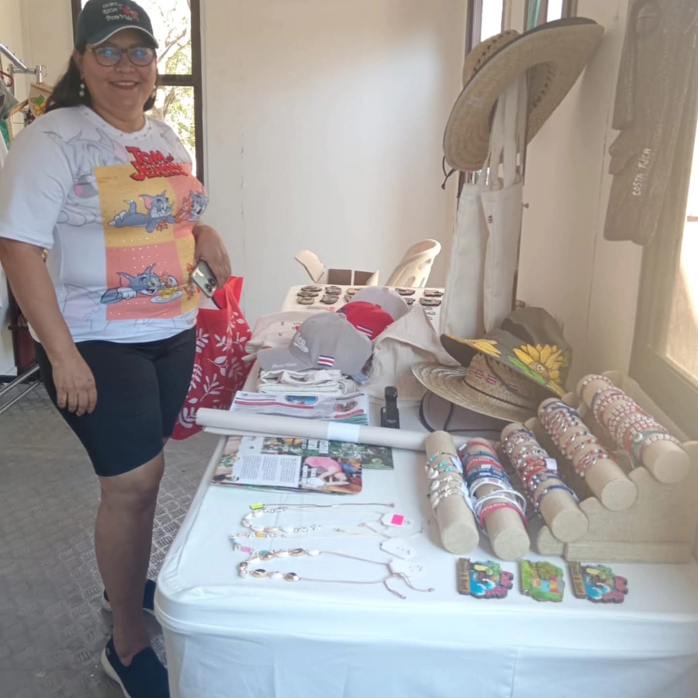 Artesana con pulseras, collares y sombrero pintado en el puesto