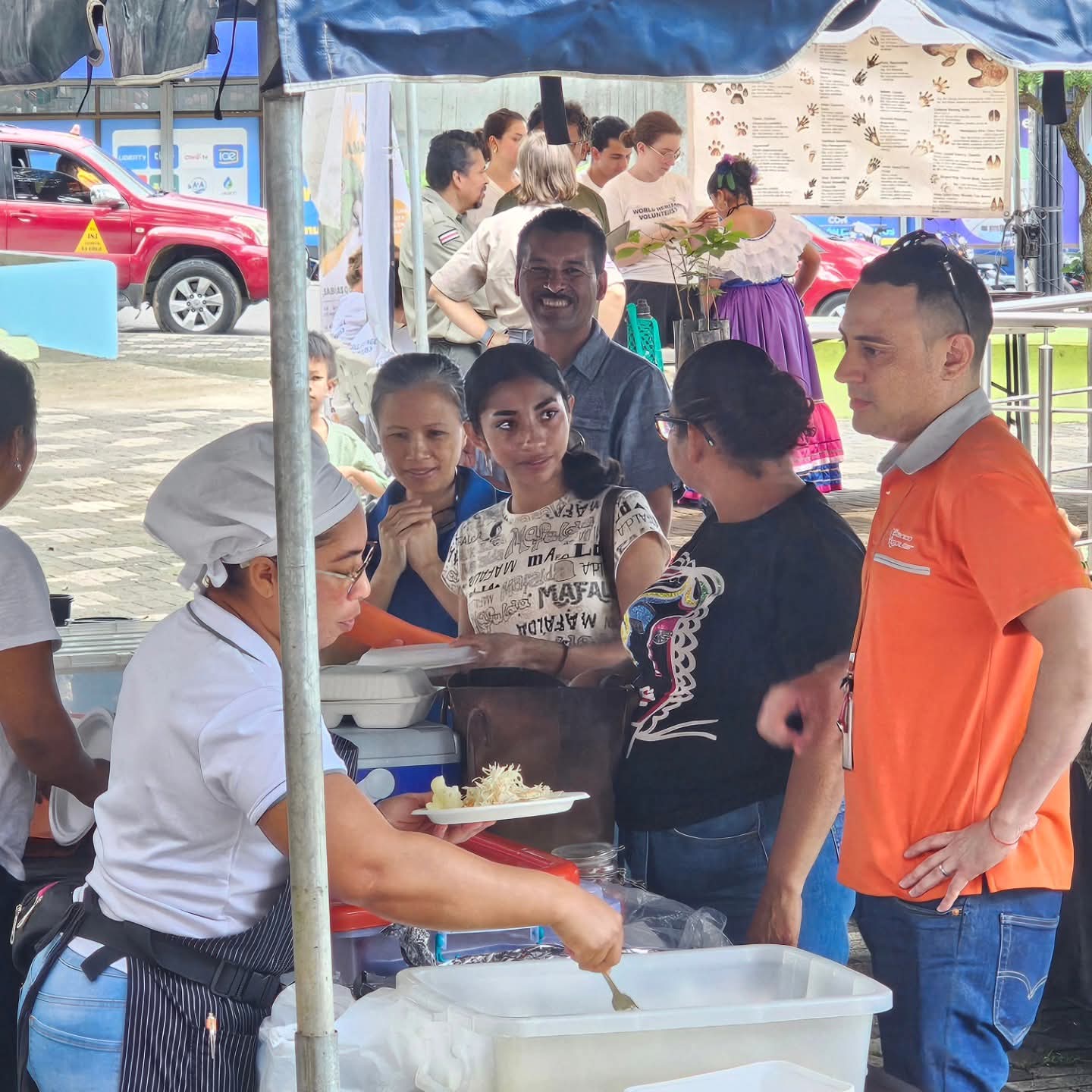 Cocina de la feria comunitaria sirviendo platos bajo el toldo