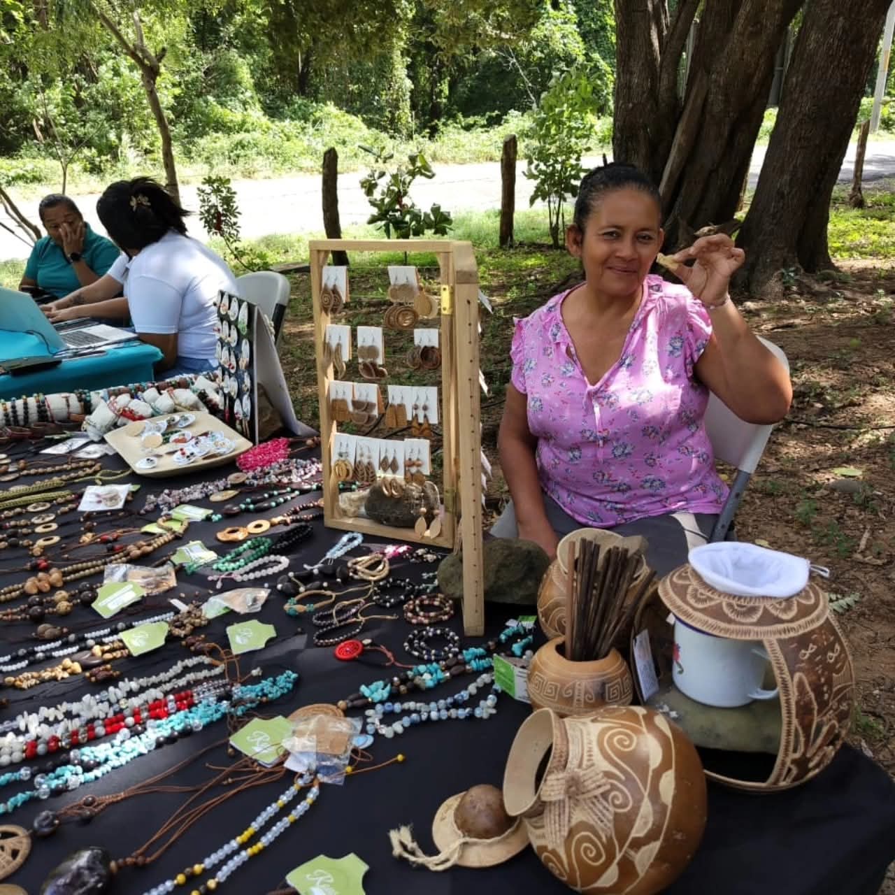 Artesana con jícaras talladas y collares de semillas en la feria
