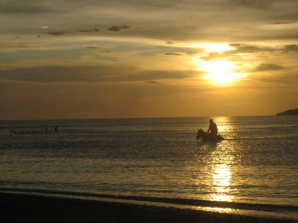 Jinete en la orilla al atardecer en una playa de La Cruz